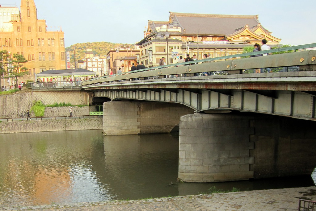 Bridge over Kamogawa River in Kyoto with city buildings and traditional architecture in Nakagyo Ward