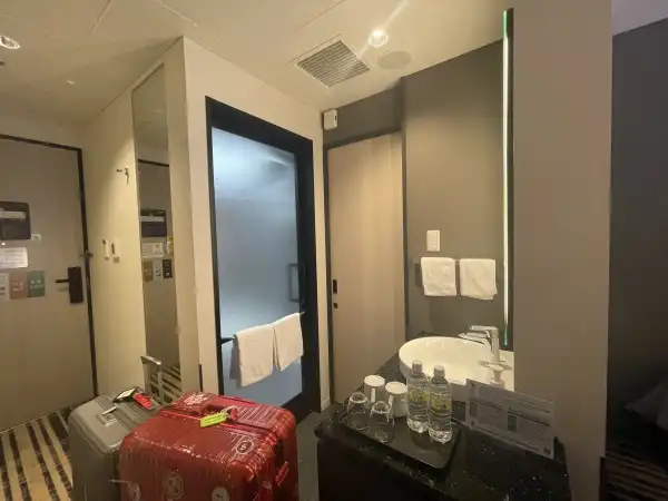Entryway and bathroom area at Hotel Hankyu RESPIRE Osaka with luggage, sink, and amenities