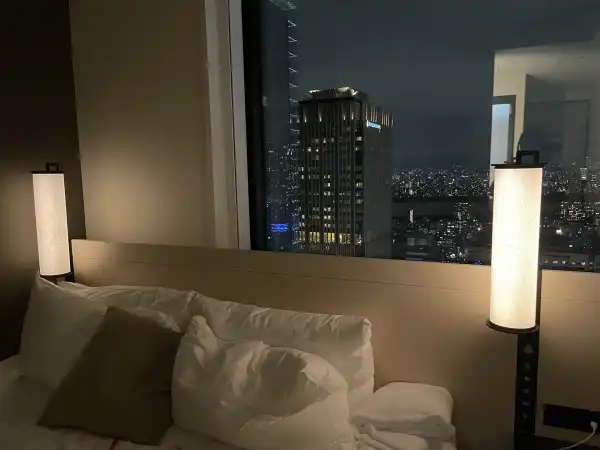 Bedside view at Hotel Hankyu RESPIRE Osaka with city skyline visible through the window at night