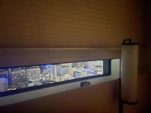 Narrow window view from Hotel Hankyu RESPIRE Osaka with Osaka city buildings visible below