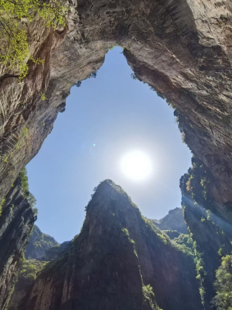 Baquan Gorge Travel Guide: How to Visit Shanxi’s Hidden Canyon Gem 7 Natural rock arch formation at Baquan Gorge with visitors walking beneath cliff opening
