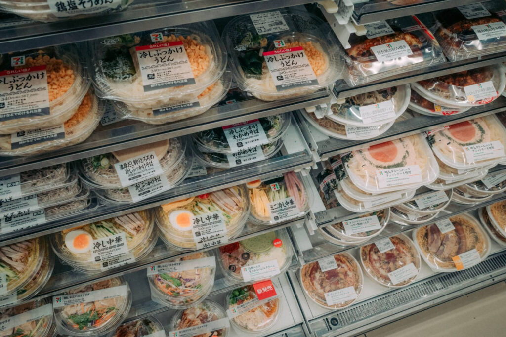 Japanese convenience store food shelf with bento boxes, rice meals and ready-to-eat items at 7-Eleven