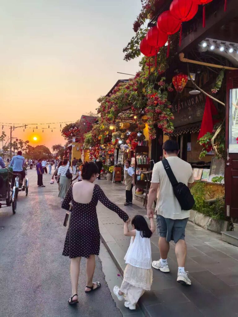 family walking in Hoi An Ancient Town at sunset with lantern shops and street view
