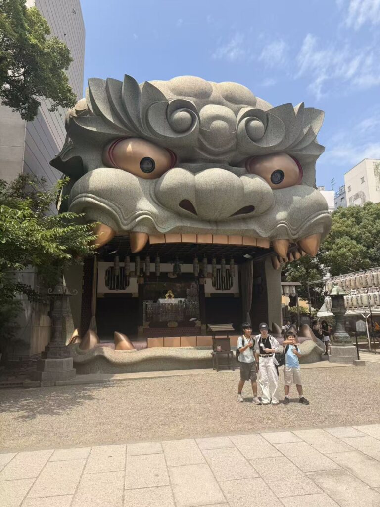 Giant lion-head stage at Namba Yasaka Shrine in Osaka under a bright blue sky.