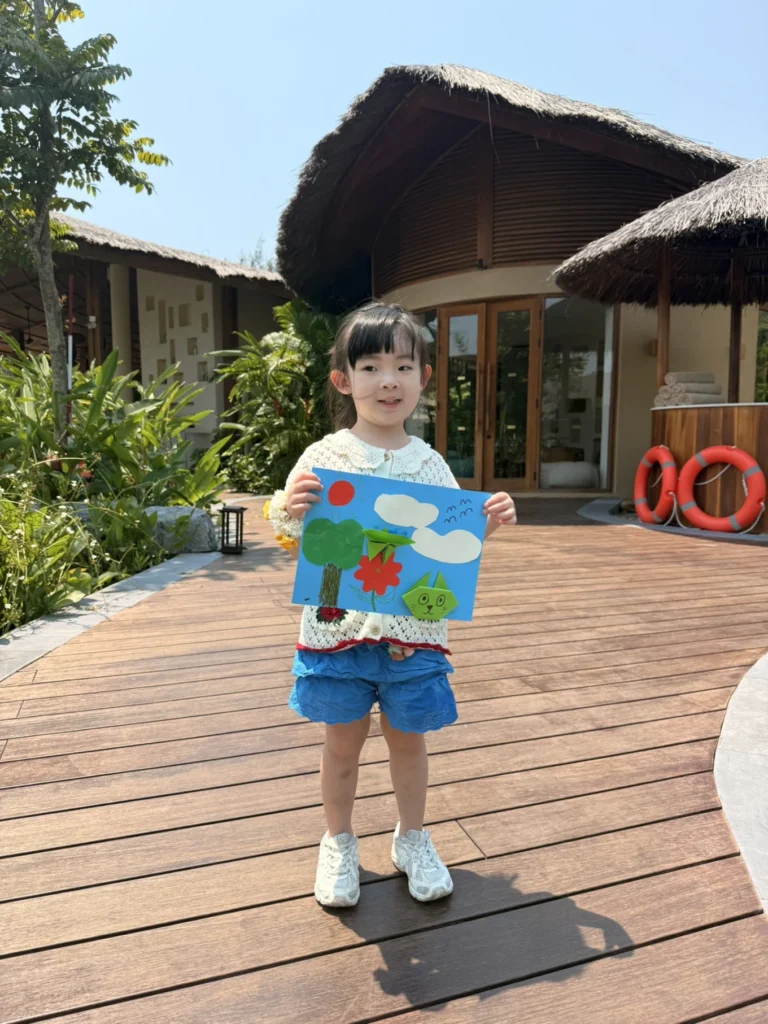 Child holding artwork at Namia River Retreat kids activity area in Hoi An
