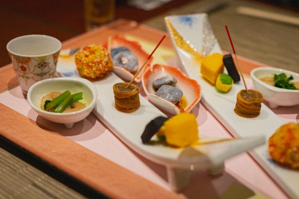 Staying at a Ryokan in Japan With Kids: What to Expect 8 Traditional Japanese kaiseki meal with multiple small dishes beautifully arranged on a tray, including seafood, vegetables, and decorative appetizers.