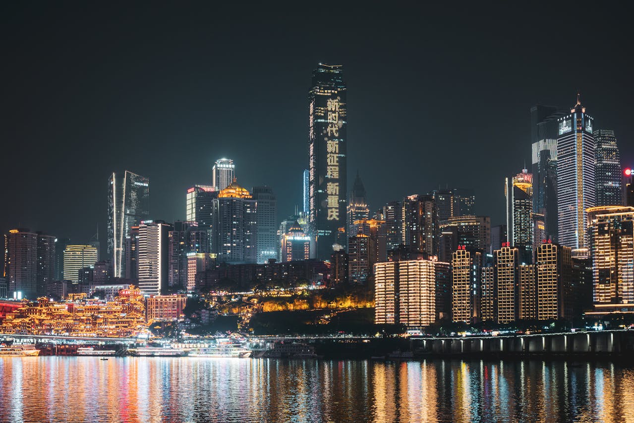 Chongqing skyline at night with illuminated skyscrapers and Hongya Cave reflecting over the Yangtze River