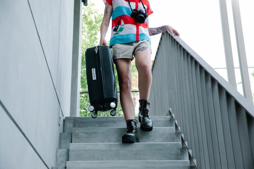 Traveler carrying a suitcase down stairs highlighting challenges of traveling with heavy luggage