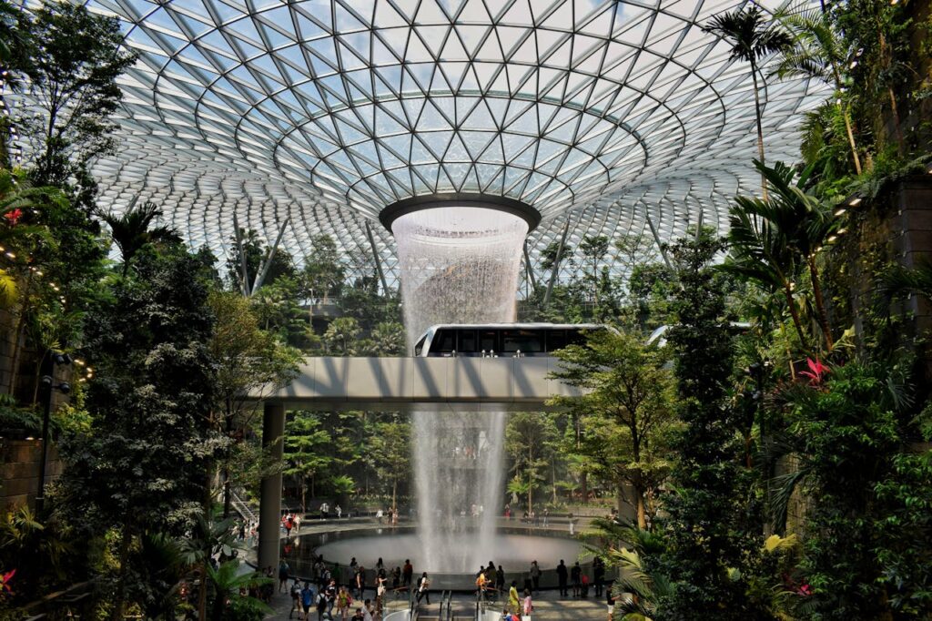 4 Best Hotels Near Changi Airport (Perfect for Layovers & Early Flights) 5 Jewel Changi Airport indoor waterfall Rain Vortex surrounded by lush greenery in Singapore