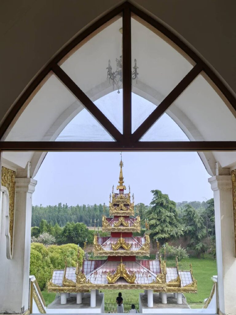 View of Thai-style pagoda at White Horse Temple through arched window frame