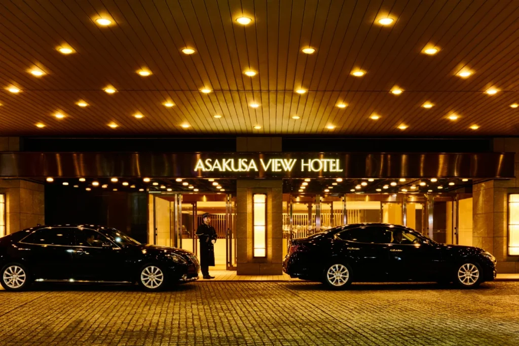 Nighttime entrance of Asakusa View Hotel in Tokyo with illuminated signage, luxury cars, and a warm upscale atmosphere near Asakusa Temple.