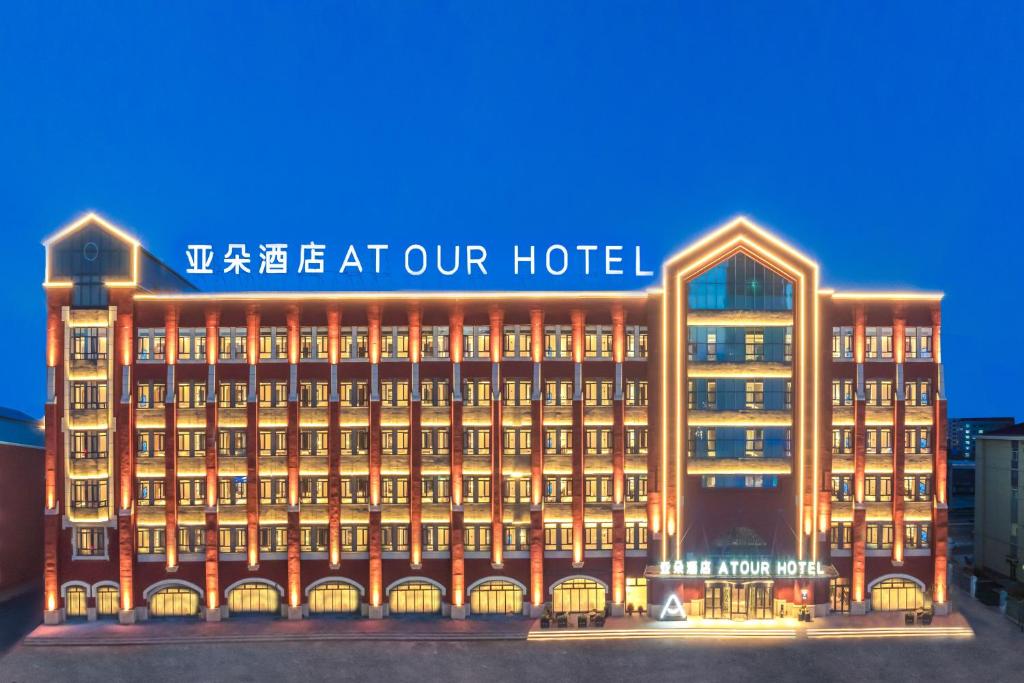 Atour Hotel Harbin Central Street illuminated at night with modern brick-style architecture and warm exterior lighting in Harbin, China.