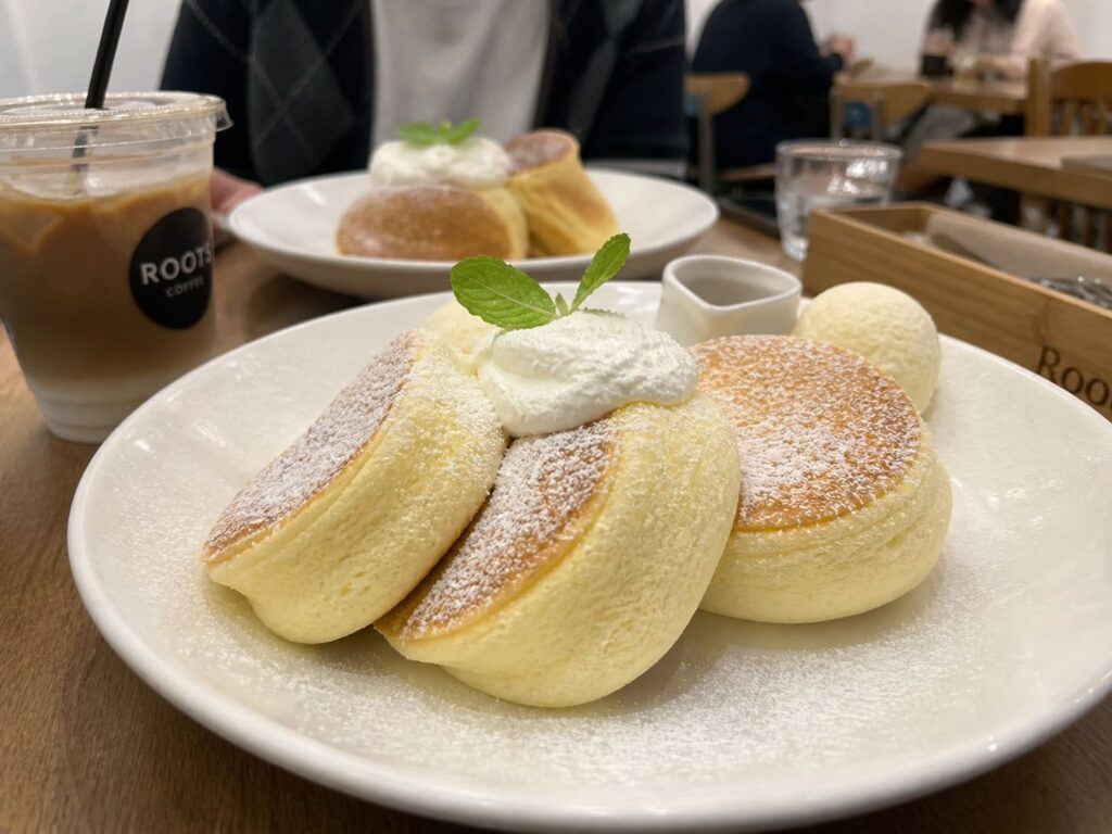 Kid-Friendly Foods to Try in Japan That Aren’t Sushi 14 Fluffy Japanese pancakes topped with whipped cream and powdered sugar in a cozy café setting