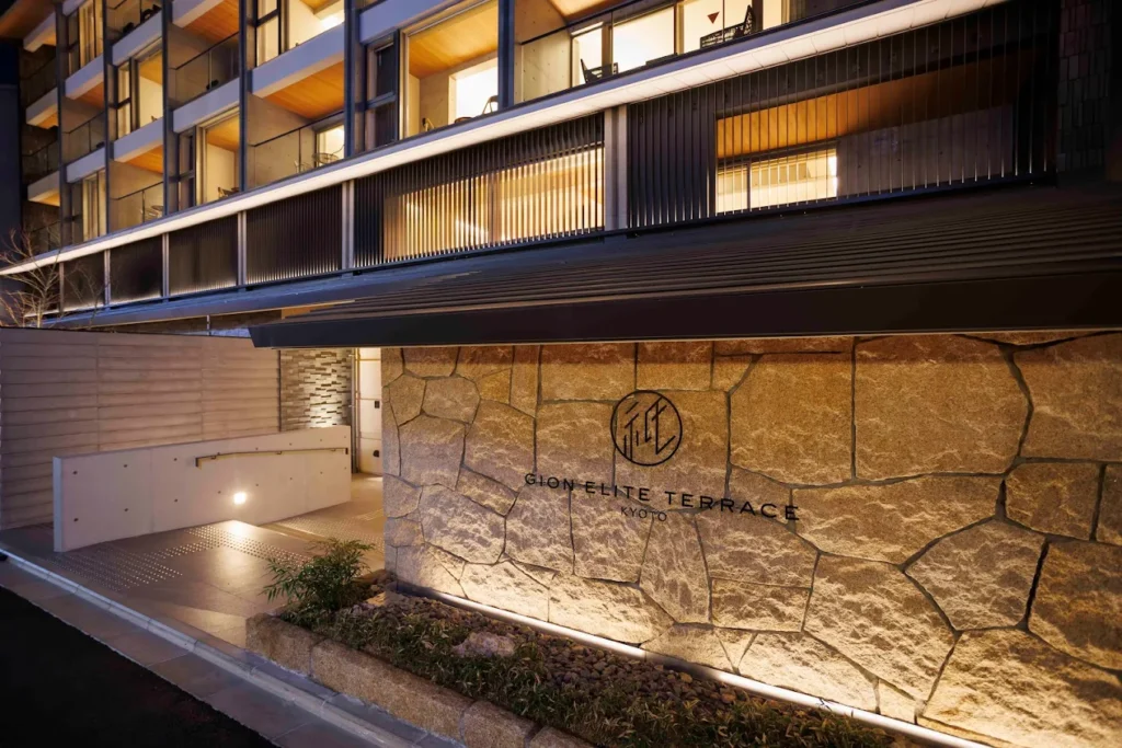 Exterior of Gion Elite Terrace Kyoto at night, featuring modern Japanese architecture, warm lighting, and a stone entrance facade in Kyoto’s Gion district.