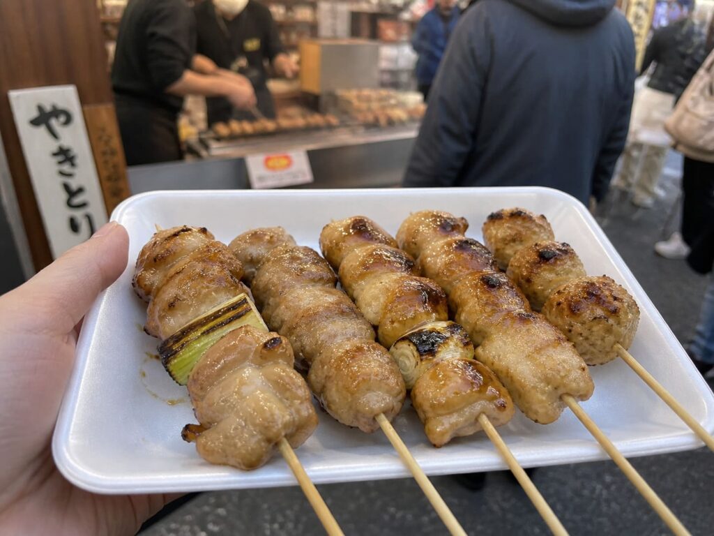 Kid-Friendly Foods to Try in Japan That Aren’t Sushi 11 Grilled chicken yakitori skewers held in hand at a busy Japanese street food market