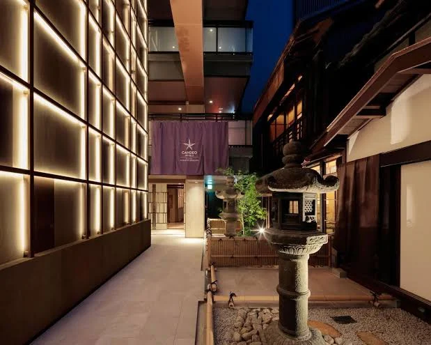 Entrance courtyard of Hotel Candel Kyoto featuring modern Japanese-inspired architecture, warm ambient lighting, and a traditional stone lantern in Kyoto, Japan.