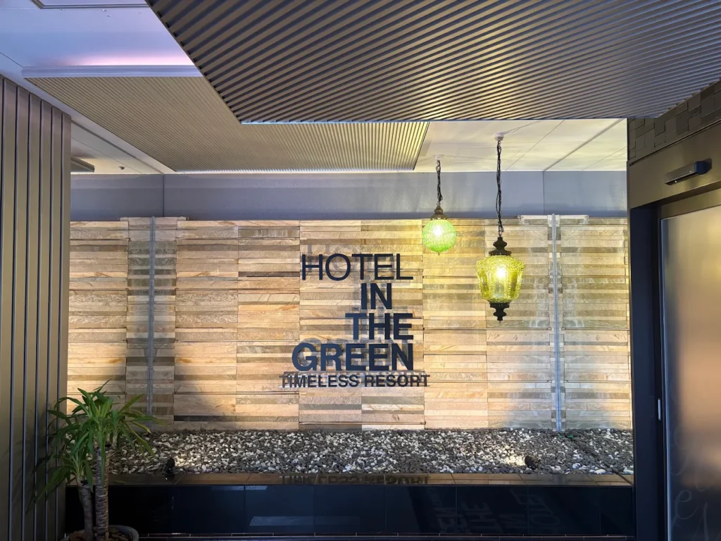 Entrance area of Hotel In The Green Kyoto featuring modern stone wall décor, warm hanging lantern lights, and minimalist resort-style design in Kyoto, Japan.