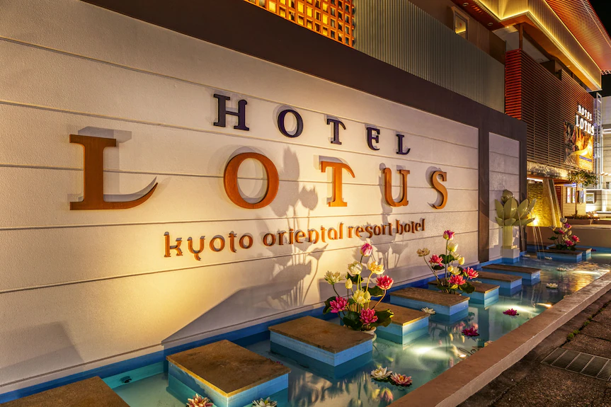 Exterior entrance of Hotel Lotus Kyoto South at night, featuring illuminated signage, warm ambient lighting, and decorative water features with floating flowers in Kyoto, Japan.