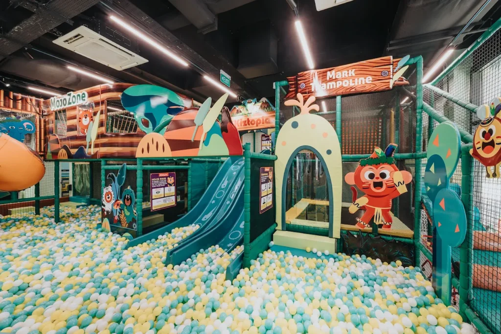 Colorful indoor playground in Singapore featuring slides, climbing structures, trampolines, and a large ball pit for children.