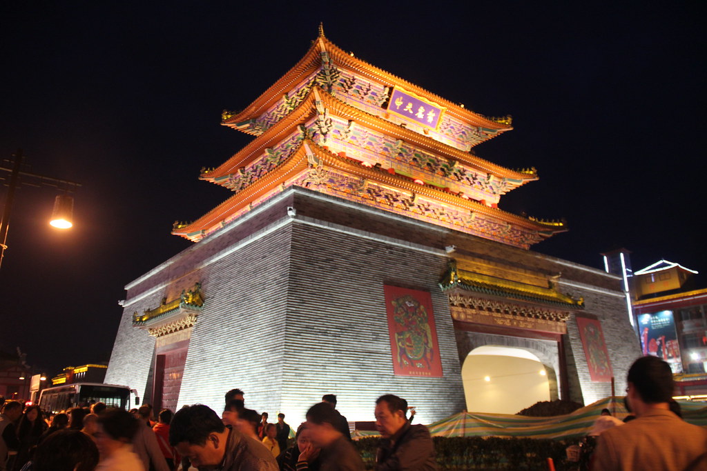 7 Underrated Cities in China Worth Visiting With Your Family 11 Illuminated traditional city gate tower at night in Kaifeng, Henan, with crowds of visitors below