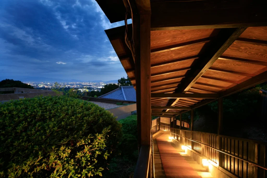 8 Best Hotels Near Nara Park: Luxury, Ryokan & Budget Stays 13 Scenic nighttime walkway at Mikasa Ryokan overlooking the city of Nara from a peaceful hillside setting