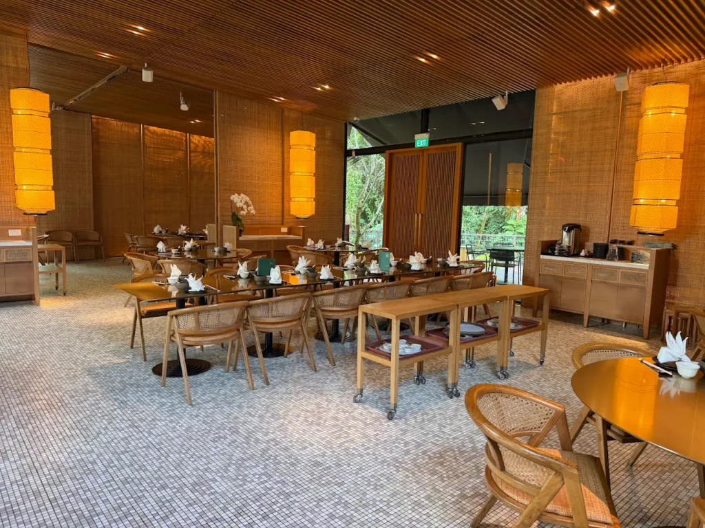 Where to Find the Best Dim Sum in Singapore (Local Picks) 14 Warm and elegant dining interior of Min Jiang at Dempsey, a refined Chinese restaurant surrounded by greenery in Singapore.