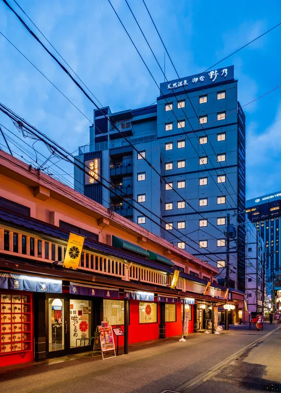 Street view of Onyado Nono Asakusa Natural Hot Spring hotel in Tokyo at dusk, featuring traditional-style storefronts and a modern Japanese ryokan-inspired building.