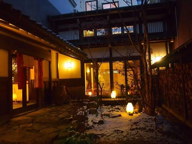 7 Best Hotels in Takayama Japan: Top Ryokans, Onsens & Family Stays 6 Traditional Japanese ryokan courtyard at night in Takayama with warm lantern lighting and snow on the ground