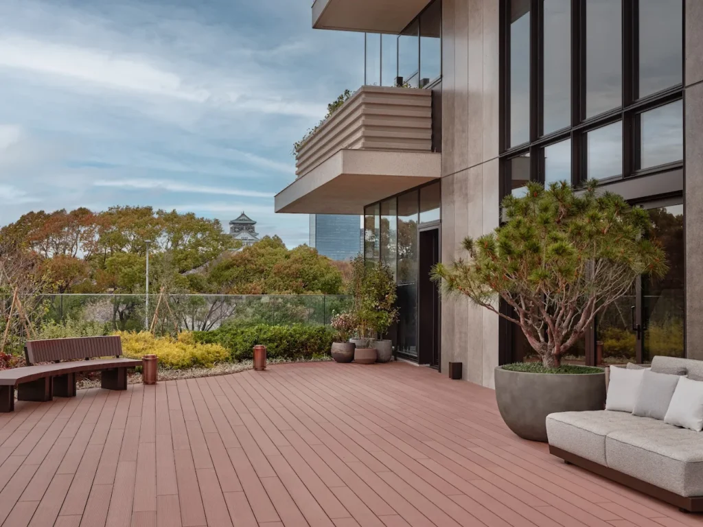 Outdoor terrace at Patina Osaka overlooking greenery and distant views of Osaka Castle, featuring modern architecture, lounge seating, and a calm luxury atmosphere.