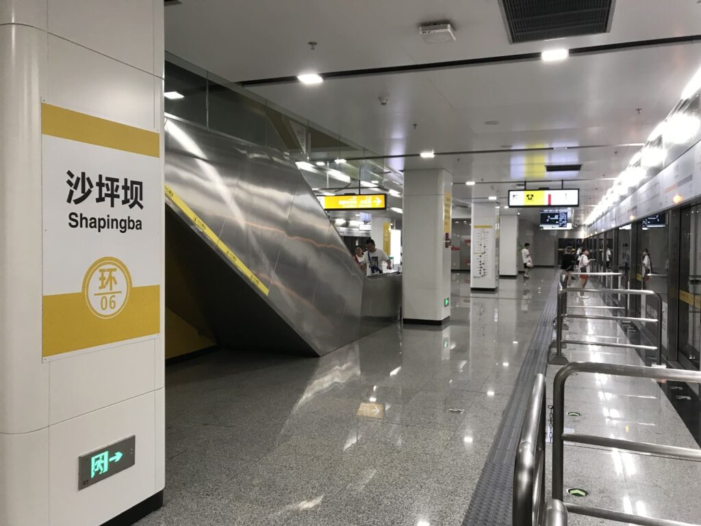 Interior of Shapingba Metro Station in Chongqing, China, showing modern subway platform signage and escalators