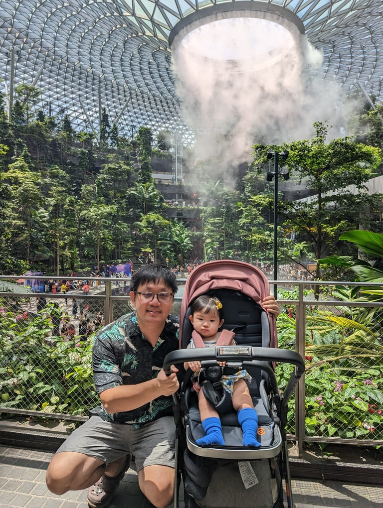 Visiting the Jewel Rain Vortex Singapore: Tips, Photos & What to Expect 8 Father and toddler posing in front of the Jewel Rain Vortex surrounded by indoor greenery at Changi Airport Singapore.