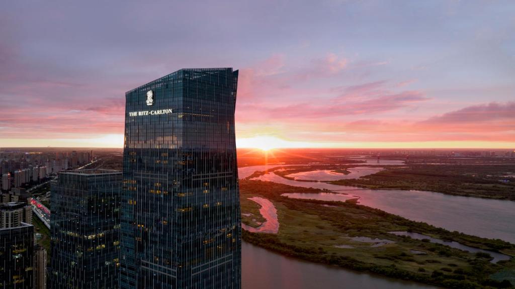 The Ritz-Carlton Harbin skyscraper at sunset overlooking the Songhua River and city skyline in Harbin, China.