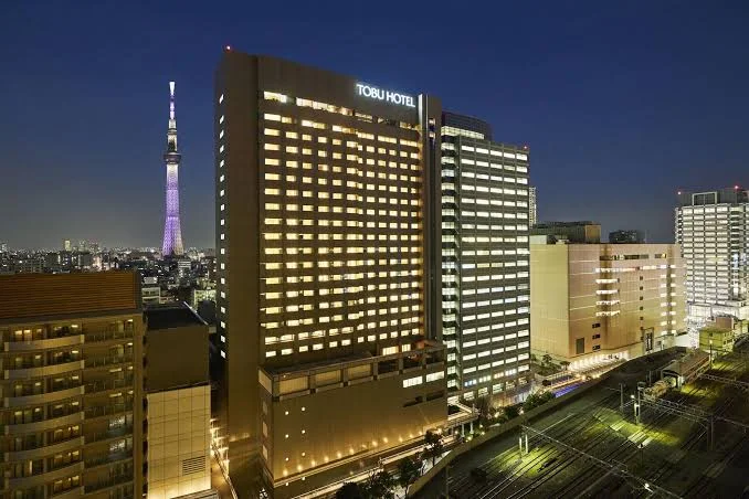 Night view of Tobu Hotel Levant Tokyo with illuminated rooms and Tokyo Skytree visible in the background near the Asakusa area.