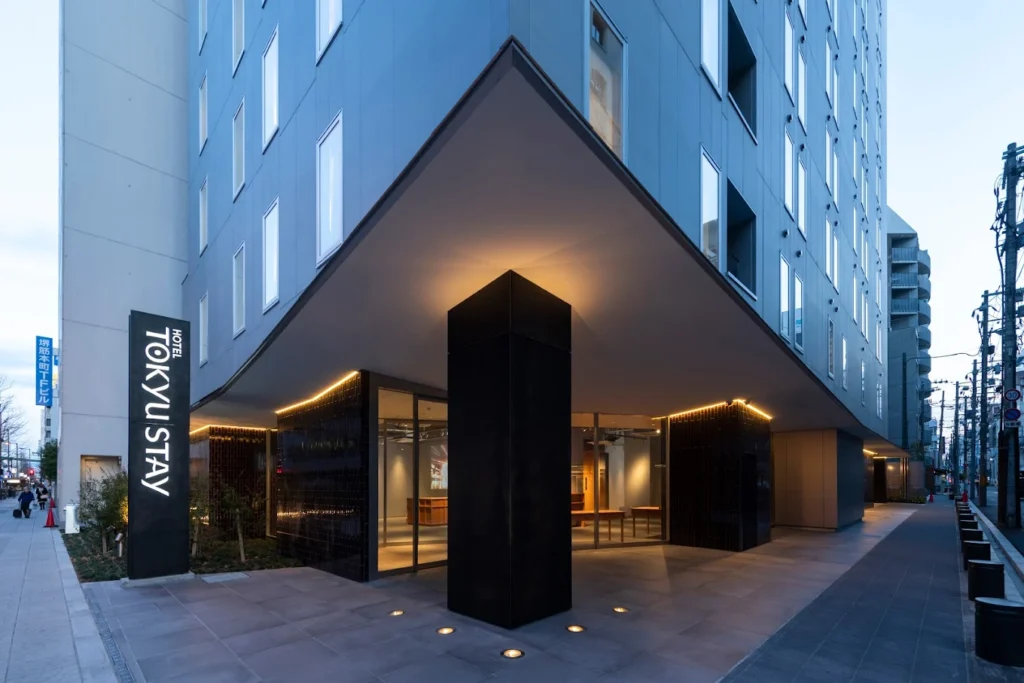 Modern exterior entrance of Tokyu Stay Osaka Honmachi hotel near Honmachi Station in Osaka at dusk