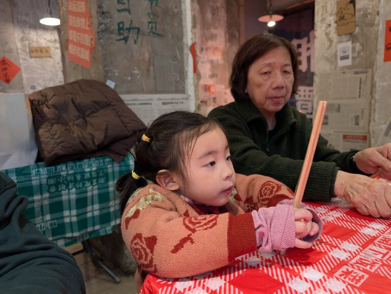 Young child learning to use chopsticks at a local family restaurant in China during a family travel