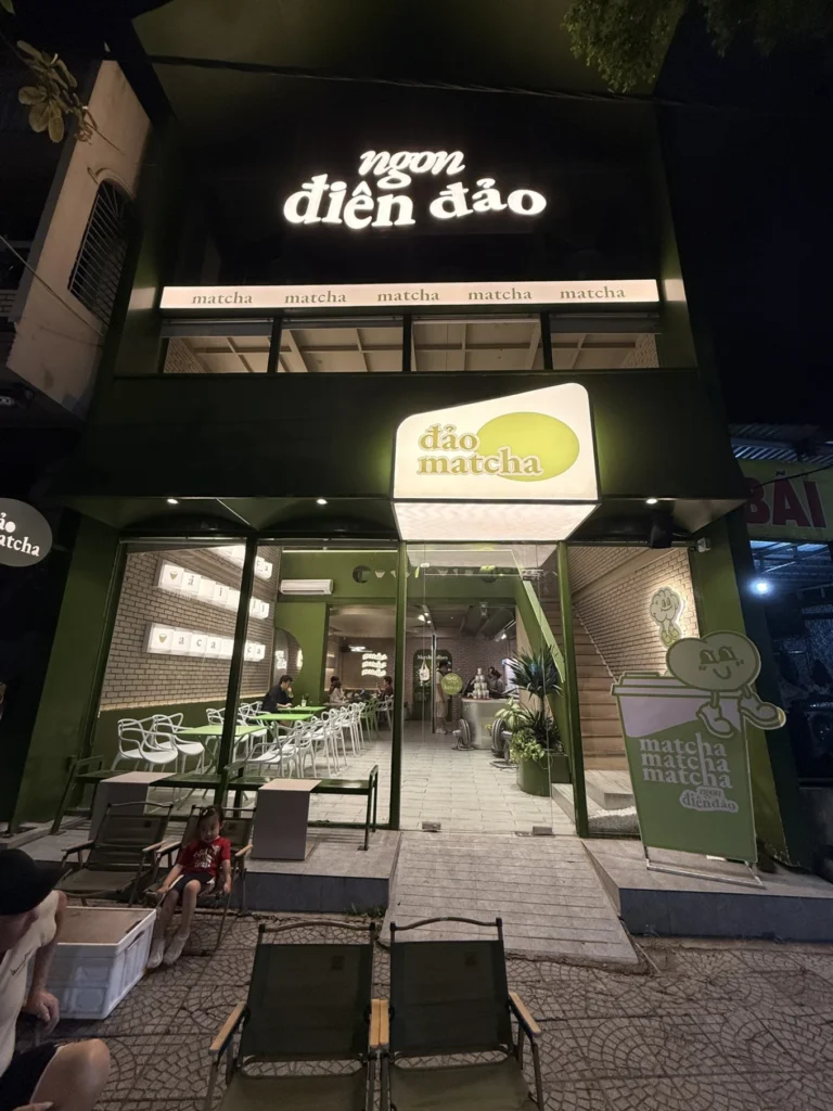 Dao Matcha café in Da Nang at night with green storefront, illuminated signage, and outdoor seating area