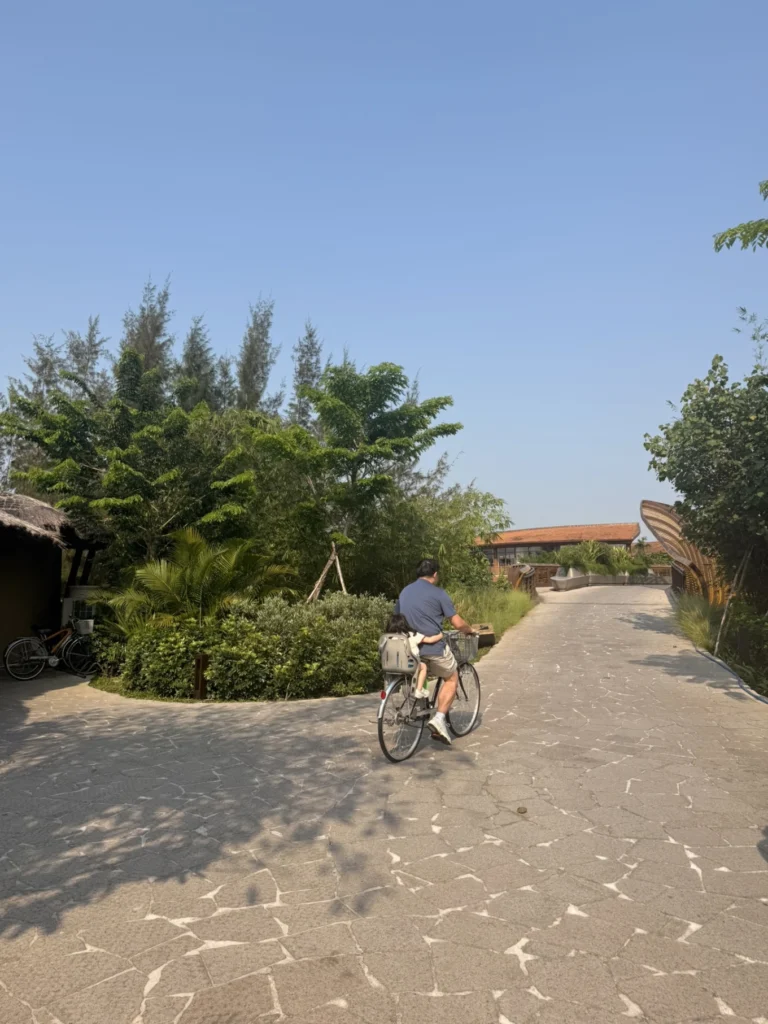 Cycling through the lush pathways of Namia River Retreat in Hoi An with tropical greenery and resort villas