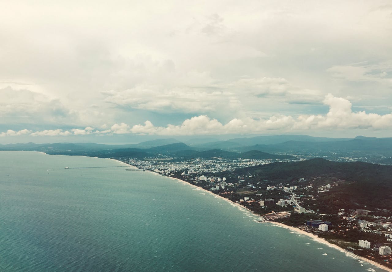 Aerial view of Cha-Am beach Thailand long coastline with sandy shore town and mountains along Gulf of Thailand