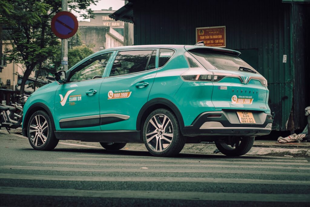 How to Get From Da Nang to Hoi An: Taxi, Bus, Motorbike & Transfer Guide 6 Green Xanh SM electric taxi parked on a street in Vietnam, commonly used for airport transfers and rides between Da Nang and Hoi An.