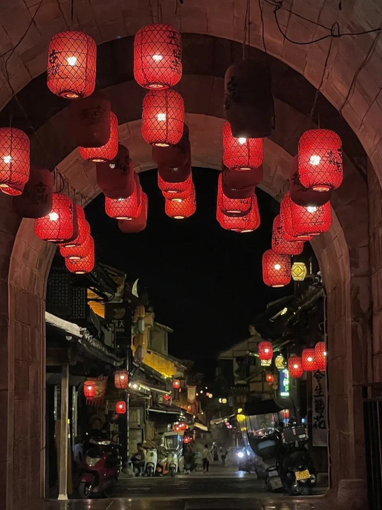 Qingyan Ancient Town Guide: Food, Night Views & Where to Stay 13 Red lanterns hanging under the ancient stone gate in Qingyan Ancient Town at night.