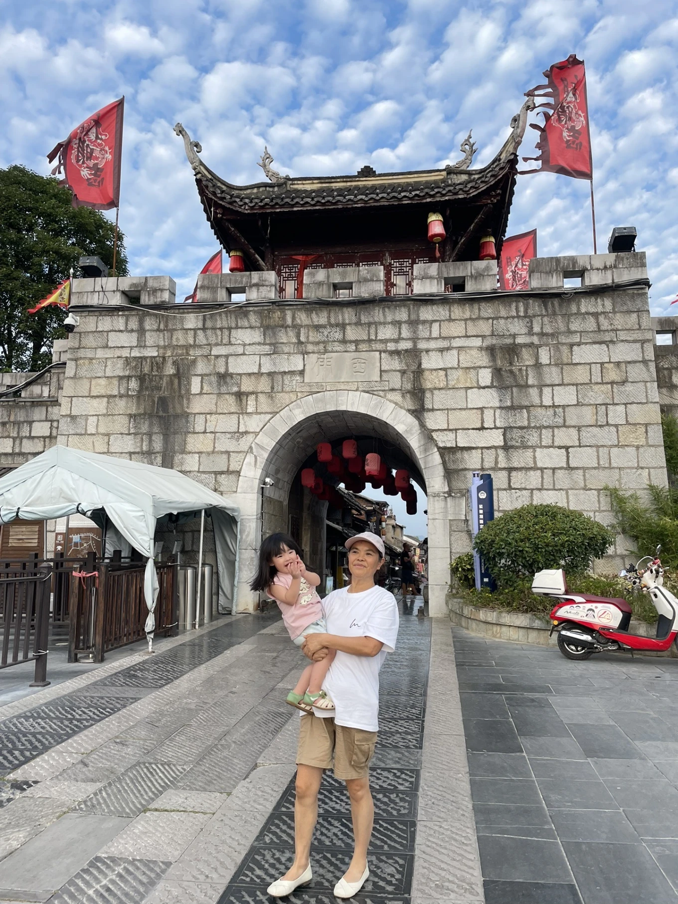 Family standing in front of the ancient west gate entrance of Qingyan Ancient Town in Guizhou.