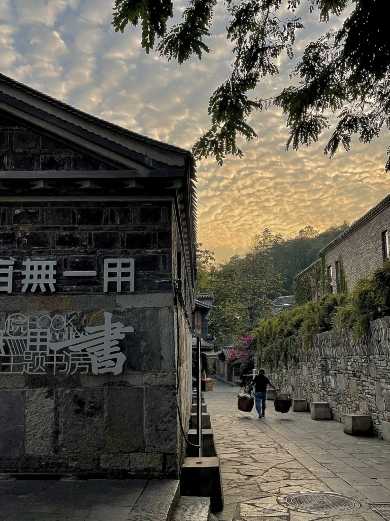 Qingyan Ancient Town Guide: Food, Night Views & Where to Stay 12 Quiet stone pathway and bookstore corner in Qingyan Ancient Town during sunset.