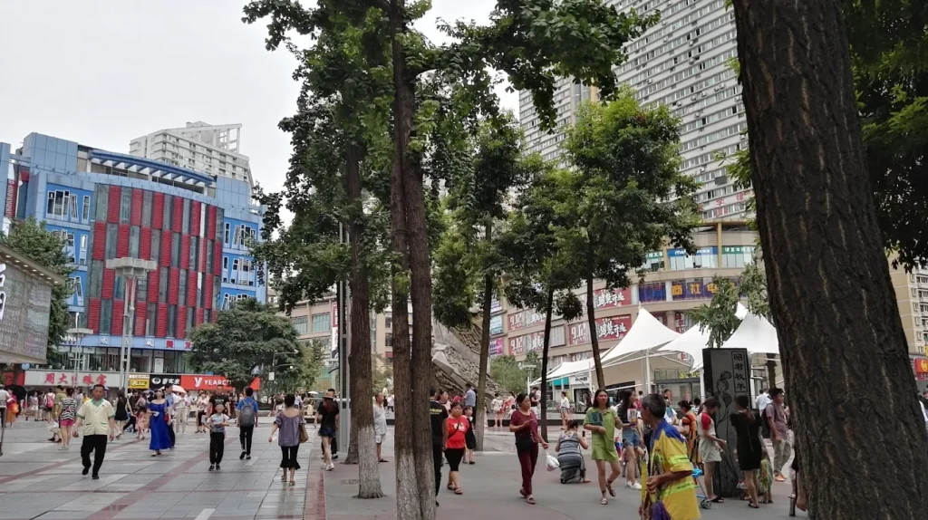 Pedestrian area at Three Gorges Square in Shapingba District Chongqing with trees, shopping malls, and crowds of locals