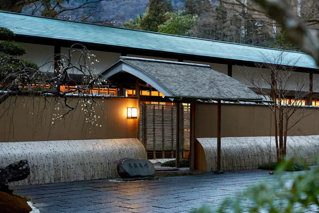 Traditional Japanese ryokan entrance at Gora Kadan in Hakone, featuring elegant architecture, landscaped gardens, and warm evening lighting.