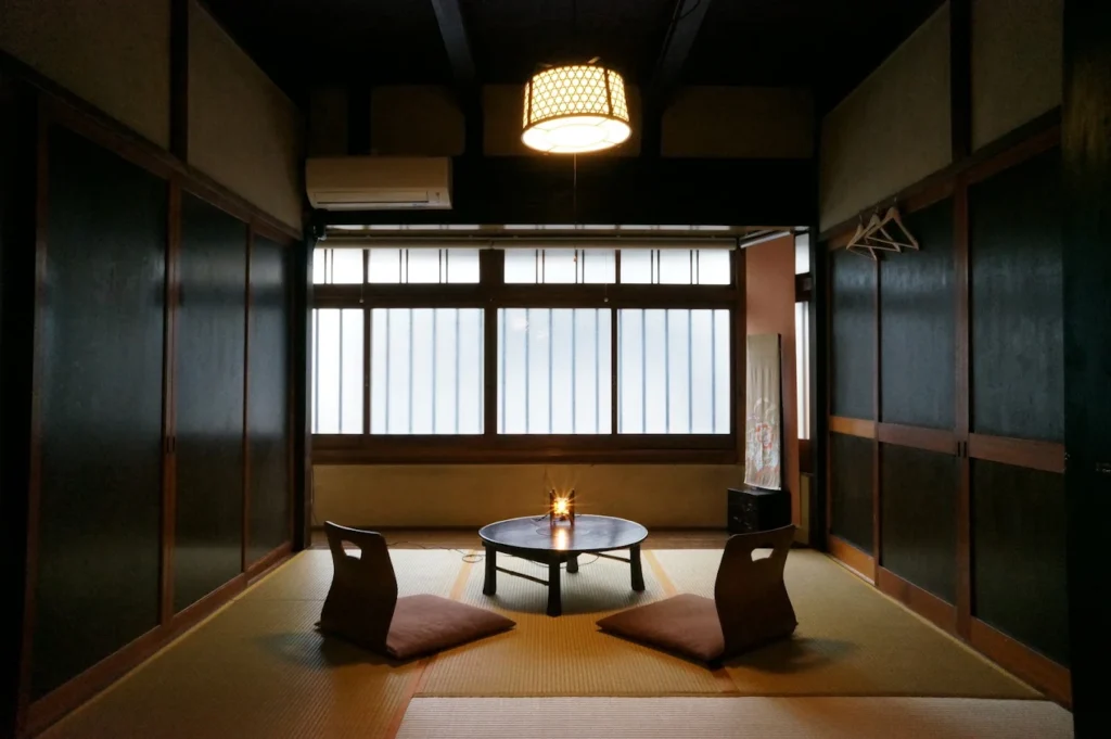 Traditional tatami room at Guesthouse Itoya Kyoto featuring Japanese floor seating, wooden interiors, and shoji-style windows