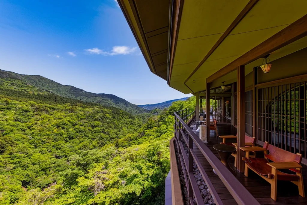 Scenic mountain view from Hakone Ginyu ryokan in Hakone, featuring a traditional Japanese terrace overlooking lush forested valleys.