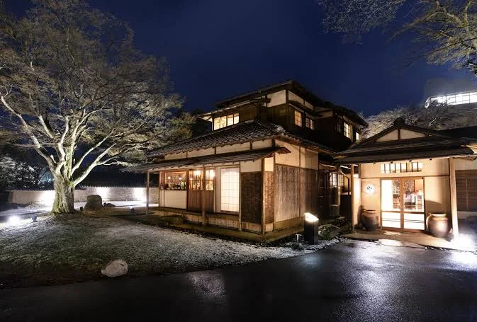 Traditional Japanese building at Hakone Suishoen illuminated at night, featuring classic ryokan architecture, landscaped grounds, and a serene atmosphere.