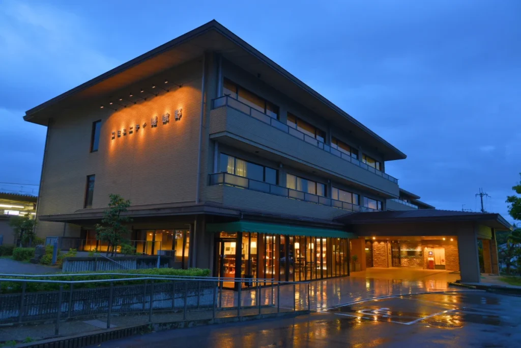 Exterior view of Hotel Binario Saga Arashiyama in Kyoto at dusk, featuring a modern hotel building with illuminated entrance and convenient access to the Arashiyama area.