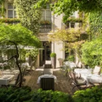 Lush private courtyard garden at Hôtel Pavillon de la Reine in Le Marais, Paris, with outdoor seating surrounded by greenery.