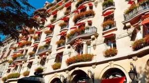 Exterior of Hôtel Plaza Athénée in Paris with red awnings, flower-filled balconies and classic Haussmann-style architecture.